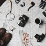 camera, pair of brown shoes, white ceramic mug, grey and black pen, brown smoking pipe