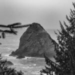 a black and white photo of a rock in the ocean